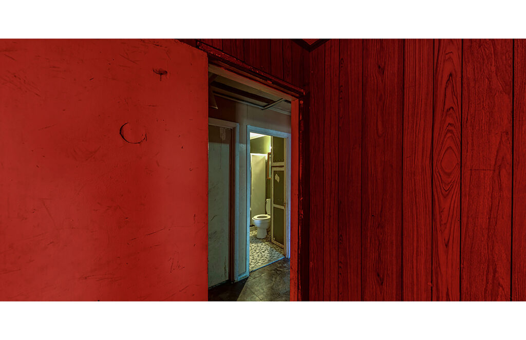 Red-painted interior with an open doorway leading through adjoining rooms to a bathroom.