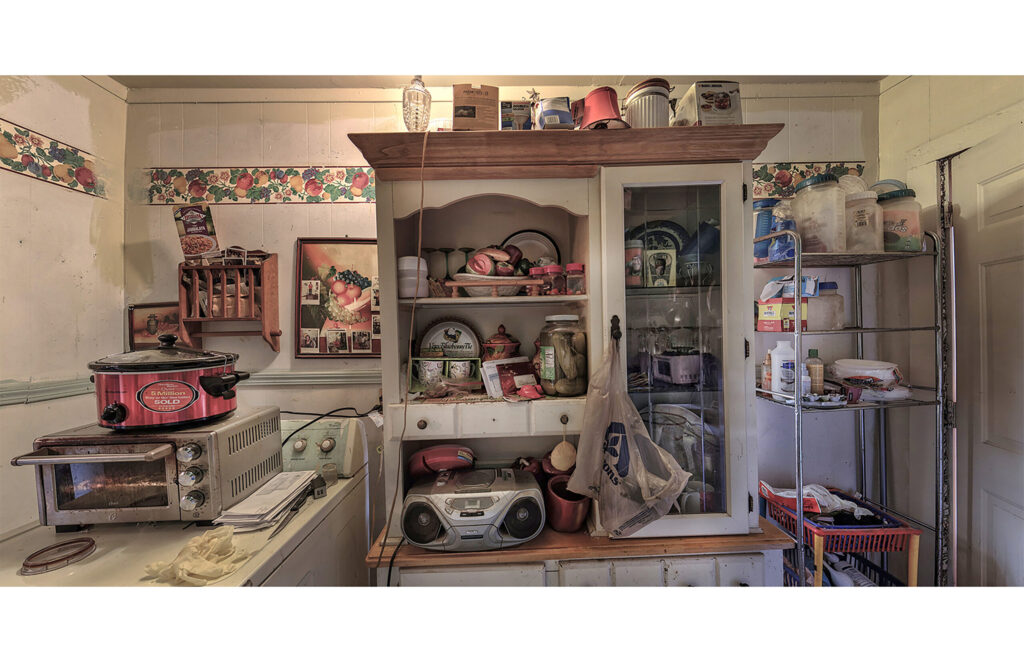 Kitchen with open shelving filled with dishes, cookware, appliances, and household supplies.